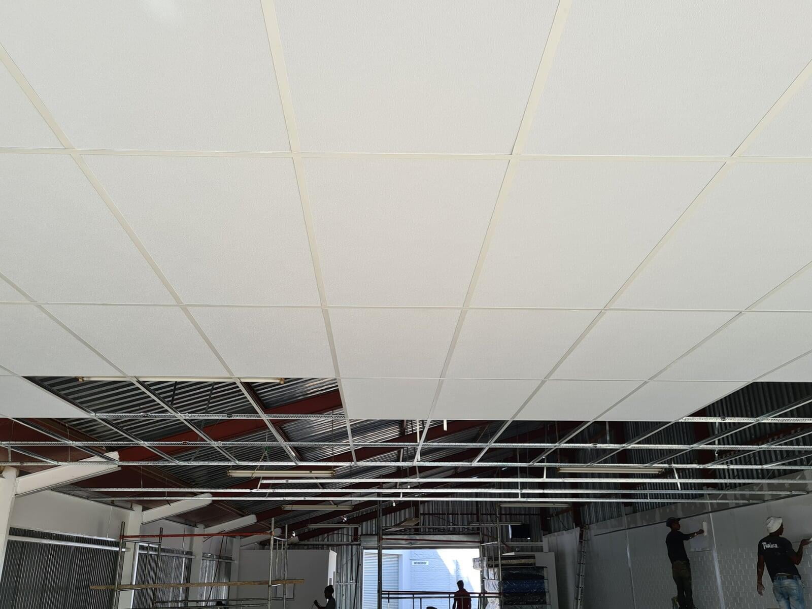 Ceiling grid and a wall being painted inside a steel-frame building