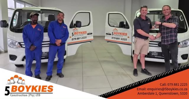 Four men with two white 5 Boykies bakkies in a tiled showroom